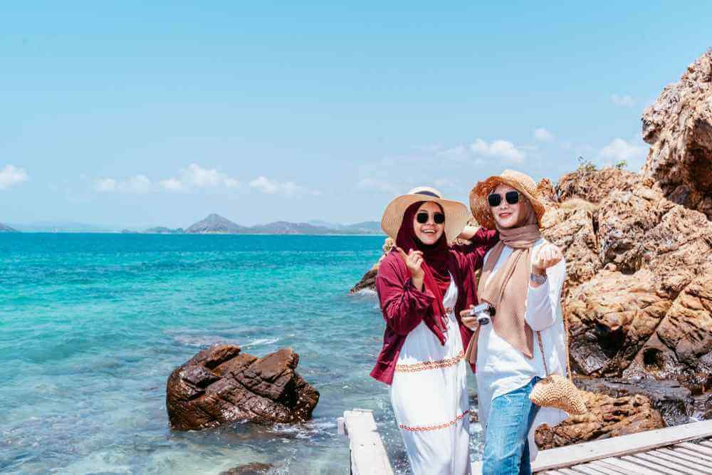 dua wanita hijab menikmati libur lebaran di pantai