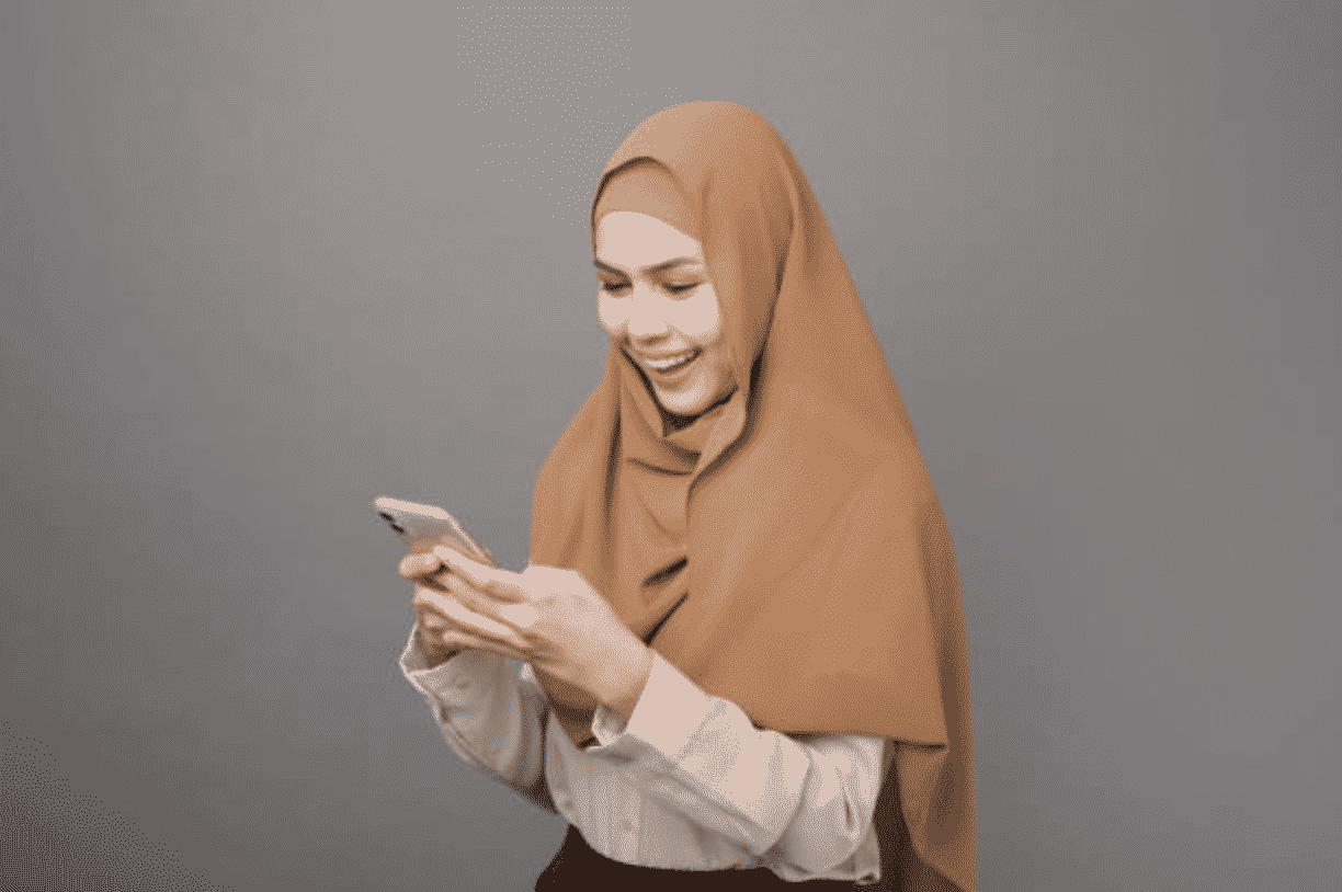wanita muslim sedang investasi saham syariah melalui smartphone